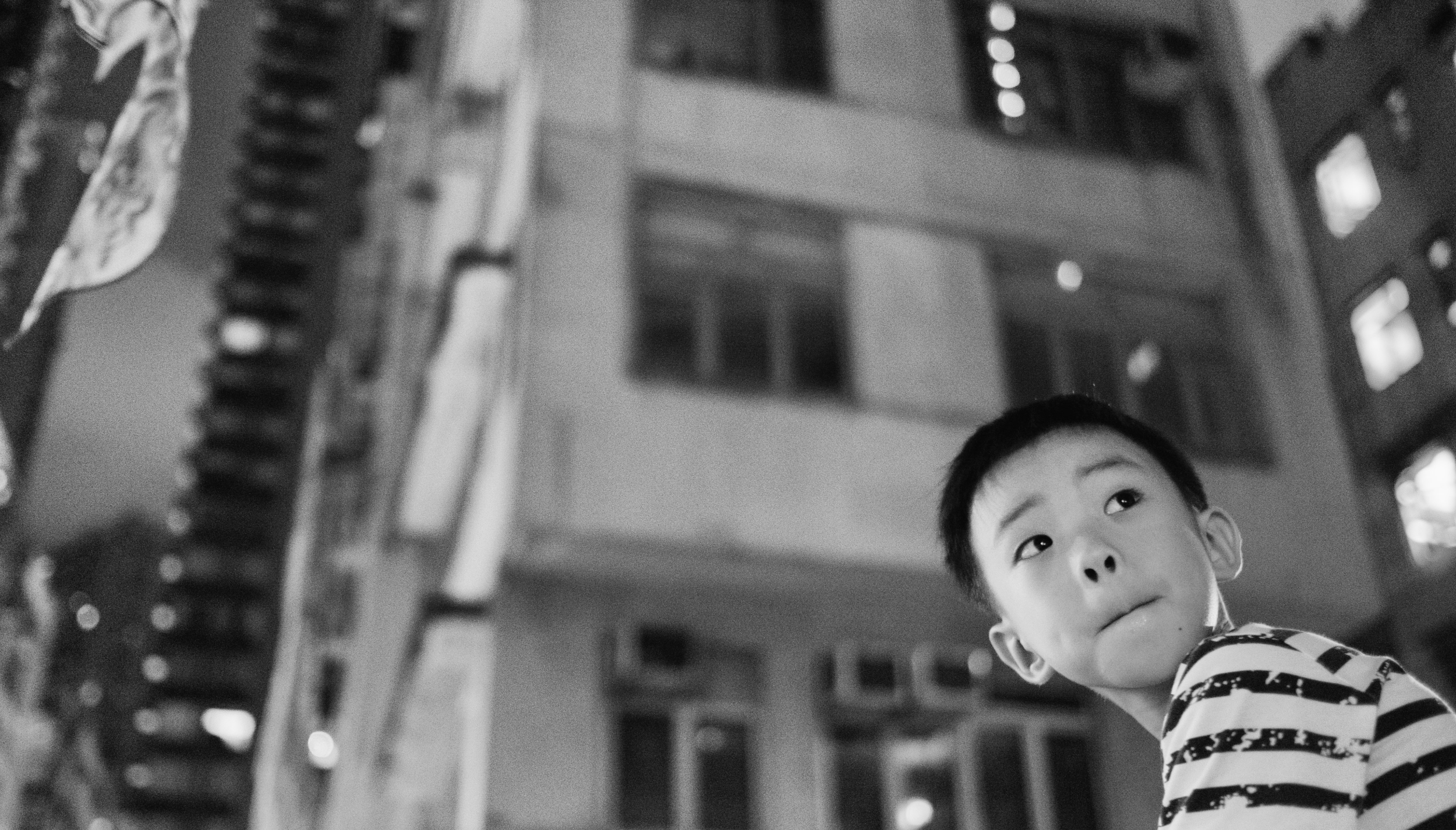 Child looking upward at night in an urban courtyard, Hong Kong