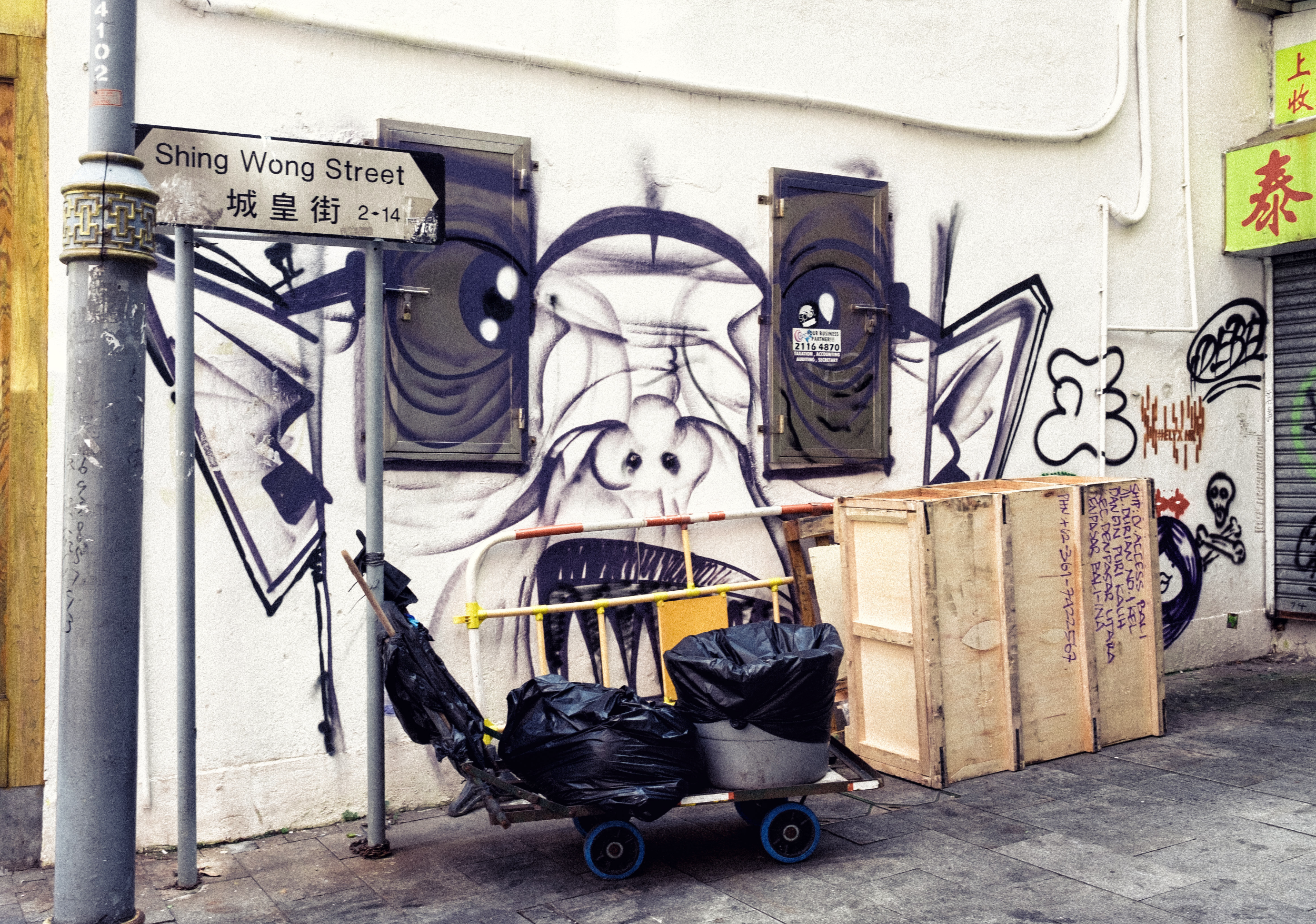 Street corner with graffiti mural, carts, and crates